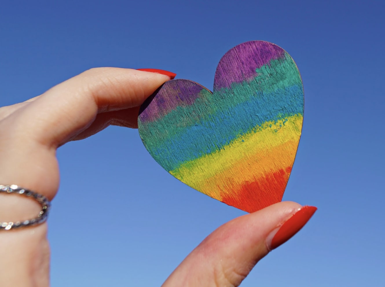 Hand holding rainbow heart