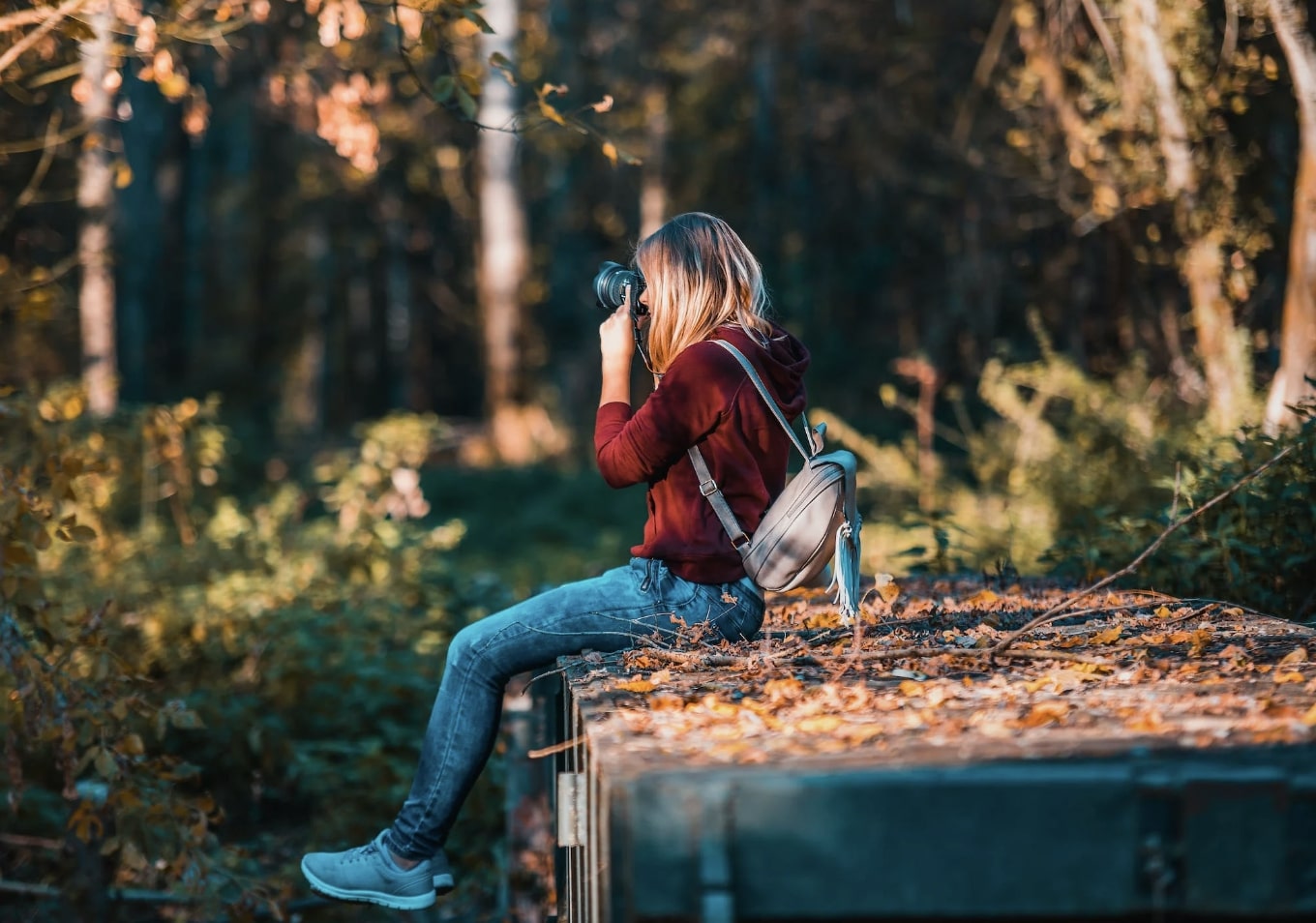 Girl Sitting Down Using Camera in Forest