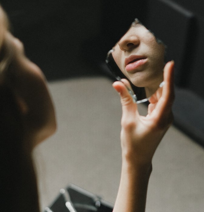 Girl looking in broken mirror