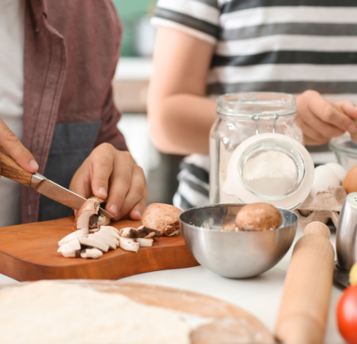 Hands preparing fresh mushrooms in a kitchen setup, showcasing Lifestyle Therapy for Youth through culinary activities.