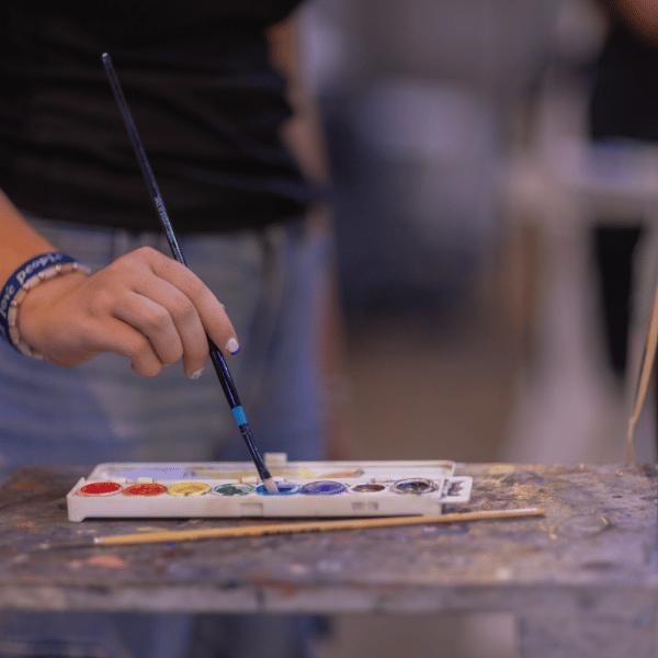 Creative Expression for Student Growth at Eva Carlston Academy: A close-up of a student’s hand using watercolors, emphasizing artistic exploration and mindfulness in the creative process.