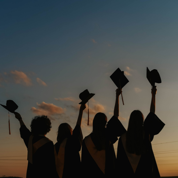 Students throwing graduation caps signifying student success at Eva Carlston