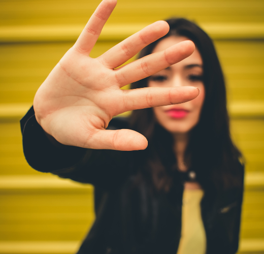 A young woman holding up her hand in a stop gesture, symbolizing setting boundaries for emotional growth and healthy relationships.