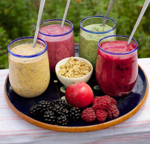 Colorful smoothies in glasses alongside fresh fruits and granola, highlighting the role of nutrition in mental health through balanced and nutrient-rich options.