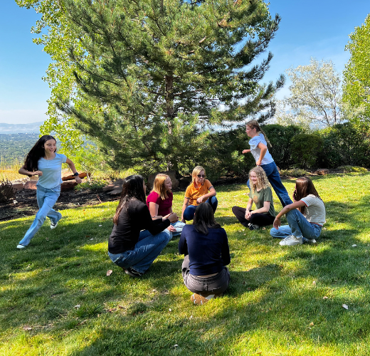 Teens engaging in emotional growth through nature for teens during a group activity on a grassy hillside.