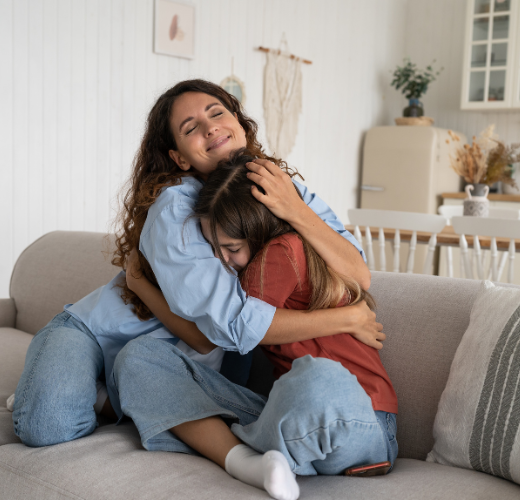 Mother and daughter hugging on a couch with visible relief and warmth, symbolizing emotional reconnection after recovering from parenting mistakes.