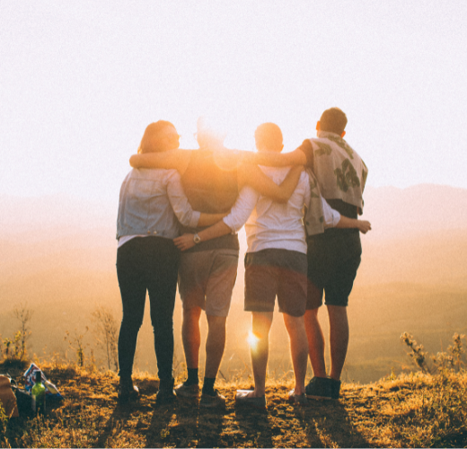 A group standing arm in arm at sunset, facing the horizon, symbolizing healing from PTSD through connection and shared strength.